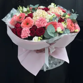 букет из красных и коралловых роз, кремовой гортензии, розовых гвоздик и белой эустомы с эвкалиптом