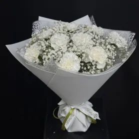 белые гвоздики и белая гипсофила в белой упаковке