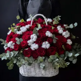 композиция из красных роз, хлопка и эвкалипта в белой корзине