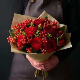 красные розы и гиперикум в букете.