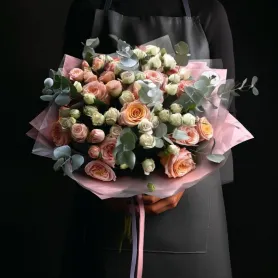 букет из персиковых и сиреневых пионовидных роз с эвкалиптом.