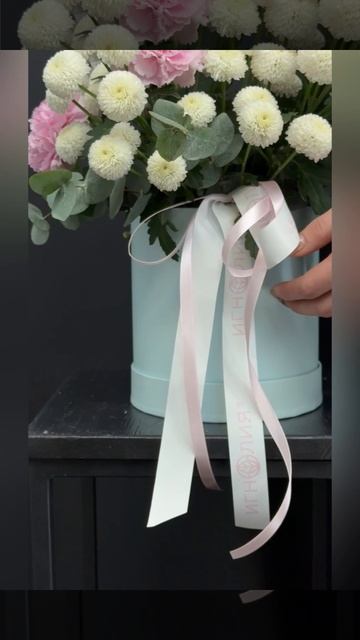 композиция из белых кустовых хризантем, кремовых гвоздик и эвкалипта в шляпной коробке