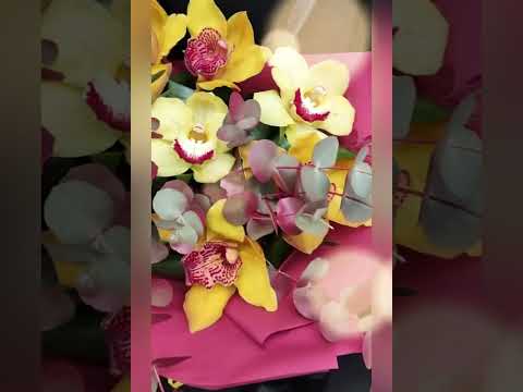 букет из жёлтых орхидей цимбидиум, розовых антуриумов и декоративной зелени в красной упаковке