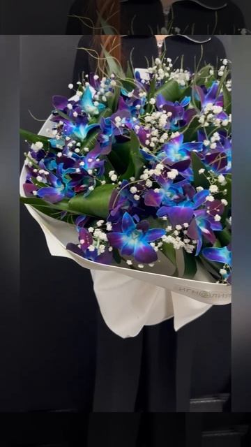 букет из синих орхидей дендробиум и белой гипсофилы в светлой упаковке